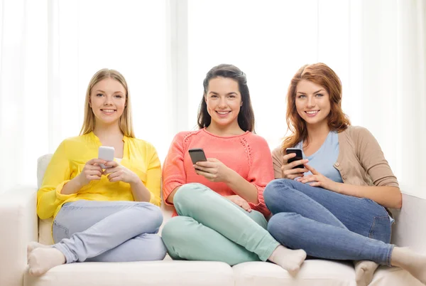 Chicas adolescentes sonrientes con teléfonos inteligentes en casa —  Fotos de Stock