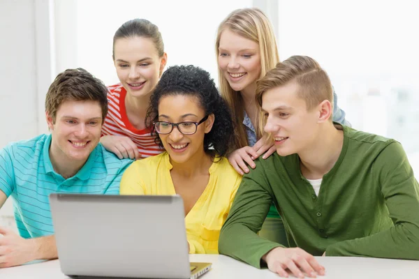 Lachende studenten kijken naar laptop op school — Stockfoto