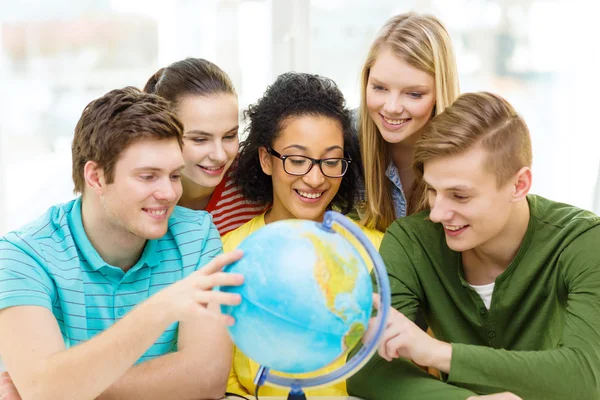 Vijf glimlachend student op zoek op wereldbol op school — Stockfoto