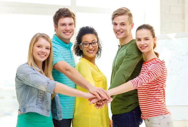 Studenti sorridenti con le mani uno sopra l'altro — Foto Stock