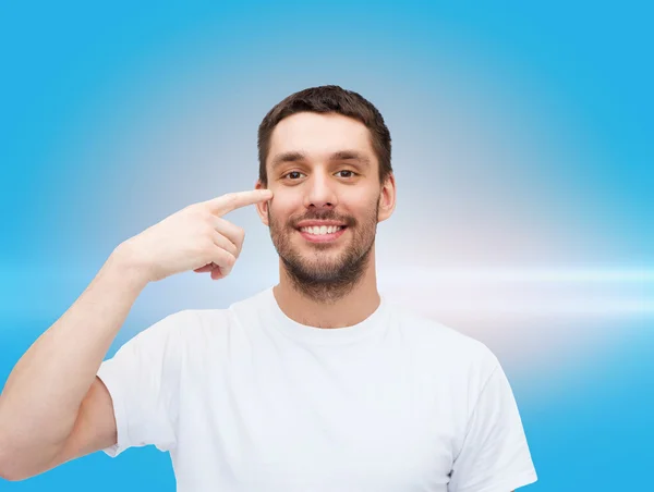 Sorrindo jovem bonito homem apontando para os olhos — Fotografia de Stock