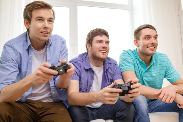 Amigos sonrientes jugando videojuegos en casa —  Fotos de Stock