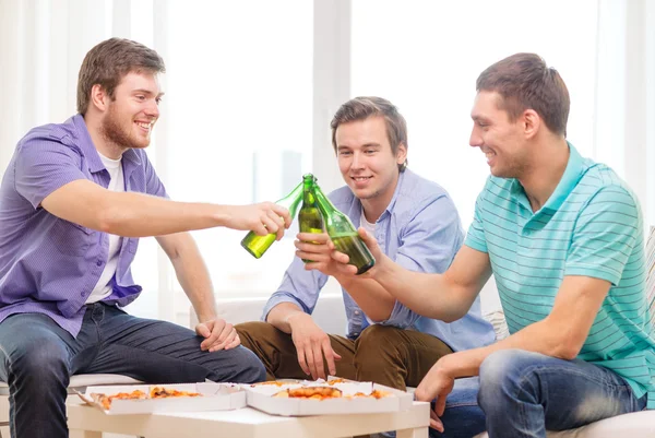 Amigos sonrientes con cerveza y pizza pasando el rato — Foto de Stock