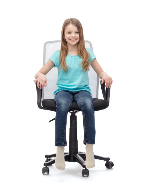 Niña sonriente sentada en una silla de oficina grande — Foto de Stock