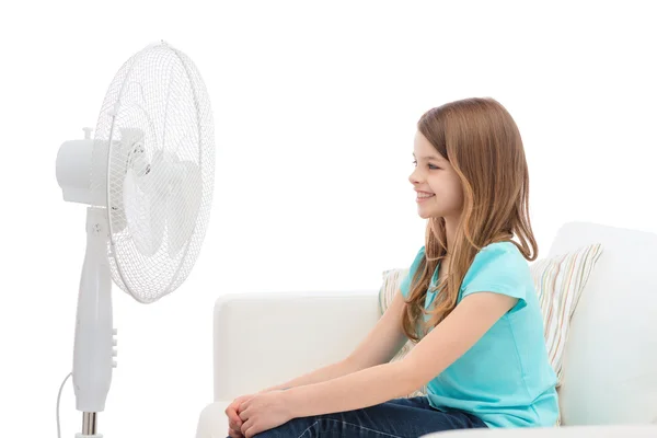 Petite fille souriante avec un grand ventilateur à la maison — Photo