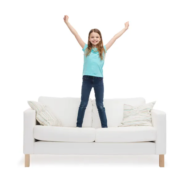 Усміхнена маленька дівчинка стрибає або танцює на дивані — стокове фото