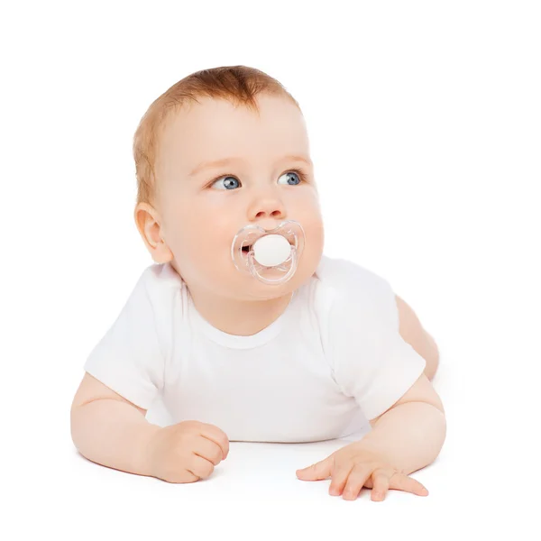 Smiling baby lying on floor with dummy in mouth — Stock Photo, Image