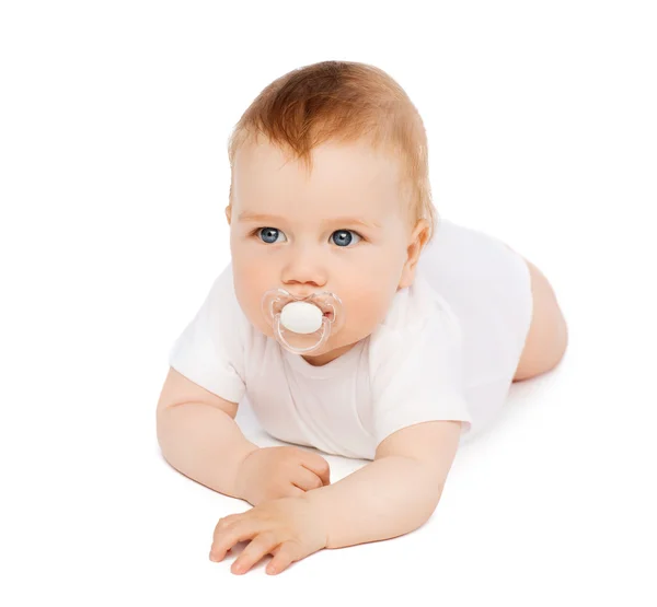 Sonriente bebé acostado en el suelo con maniquí en la boca —  Fotos de Stock