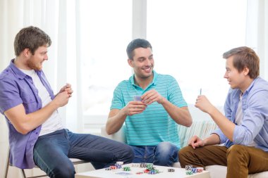 happy three male friends playing poker at home clipart