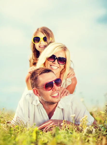 Família feliz com céu azul e grama verde — Fotografia de Stock
