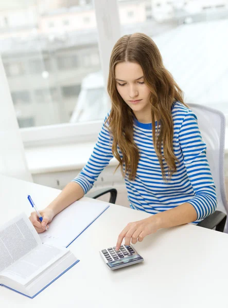 Menina estudante com livro, calculadora e notebook — Fotografia de Stock