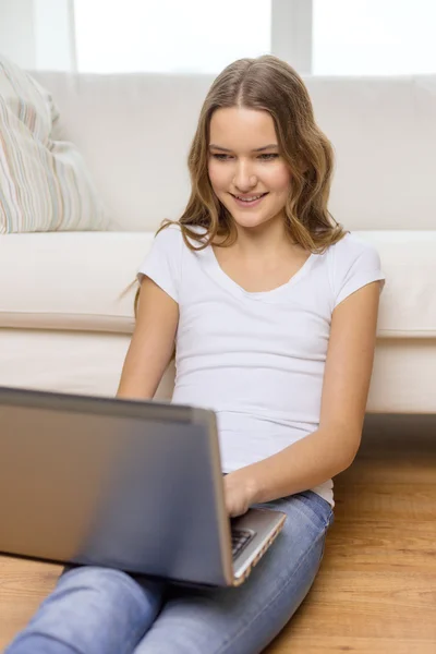 Sonriente adolescente con ordenador portátil en casa — Foto de Stock