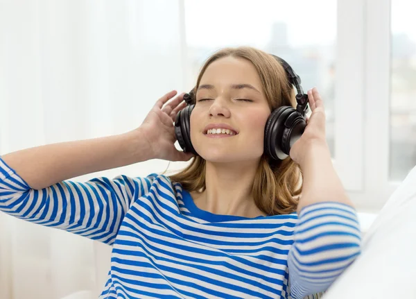 Lächelndes junges Mädchen mit Kopfhörern zu Hause — Stockfoto