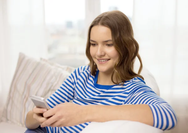 Sorrindo adolescente com smartphone em casa — Fotografia de Stock