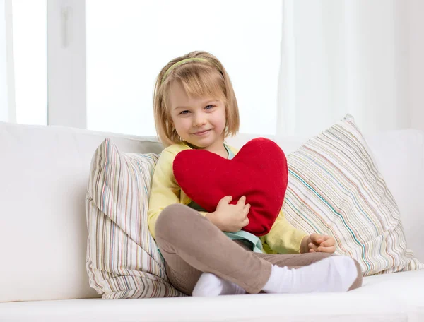 Leende liten flicka med rött hjärta hemma — Stockfoto