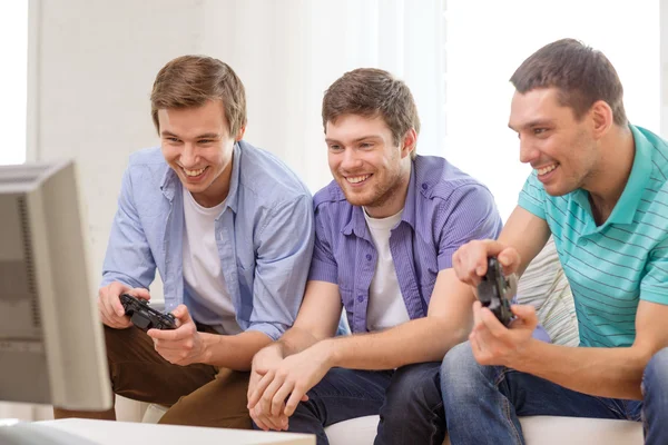Amigos sonrientes jugando videojuegos en casa — Foto de Stock