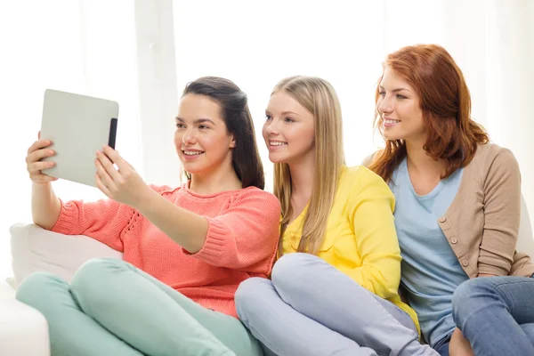 Drie lachende tienermeisjes met tablet pc thuis — Stockfoto