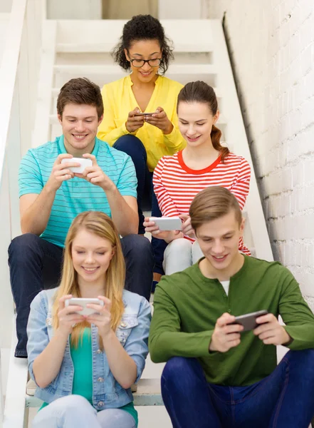 Smiling students with smartphone texting at school — Stock Photo, Image