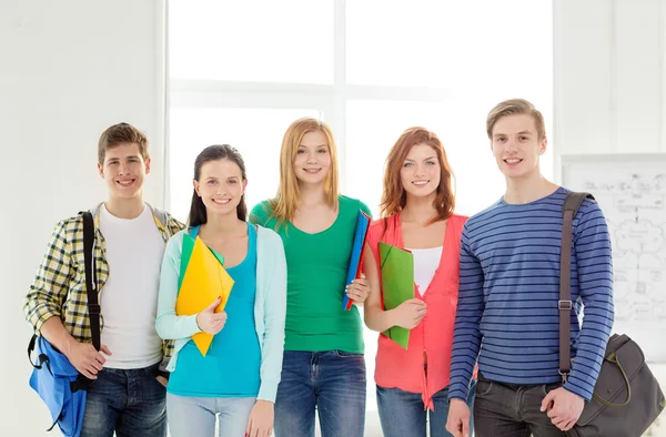 Lachende studenten met tassen en mappen op school — Stockfoto