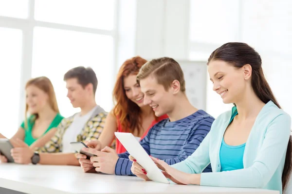 Lachende studenten met de tablet pc op school — Stockfoto