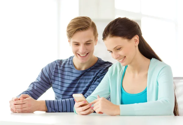 Two smiling students with smartphone at school — Stock Photo, Image