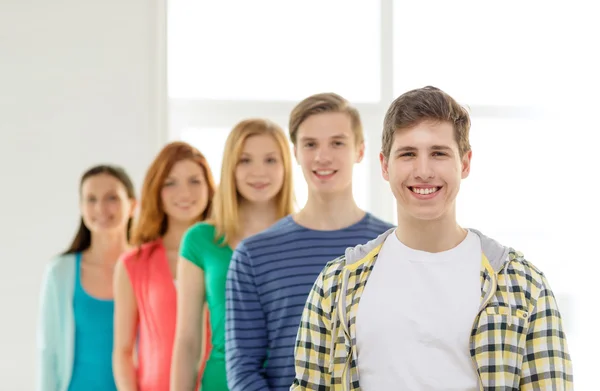 Smiling students with teenage boy in front — Stock Photo, Image