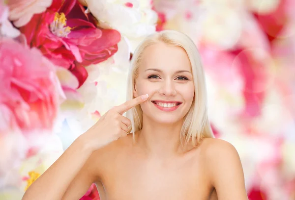 Smiling young woman pointing to her nose — Stock Photo, Image