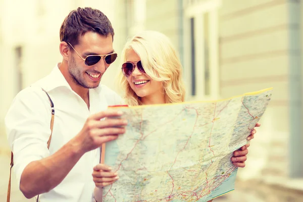 Pareja sonriente en gafas de sol con mapa en la ciudad —  Fotos de Stock