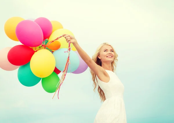 Femme souriante avec des ballons colorés à l'extérieur — Photo