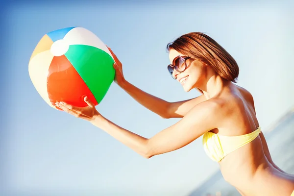 Девушка в бикини играет в мяч на пляже — стоковое фото