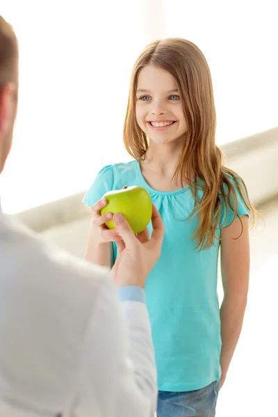 Arzt schenkt lächelndem kleinen Mädchen einen Apfel — Stockfoto