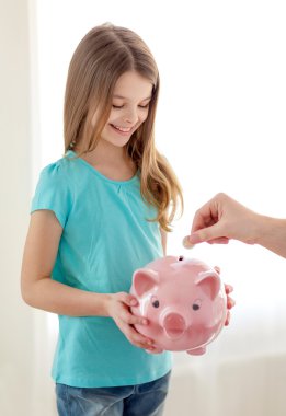 smiling little girl holding piggy bank clipart