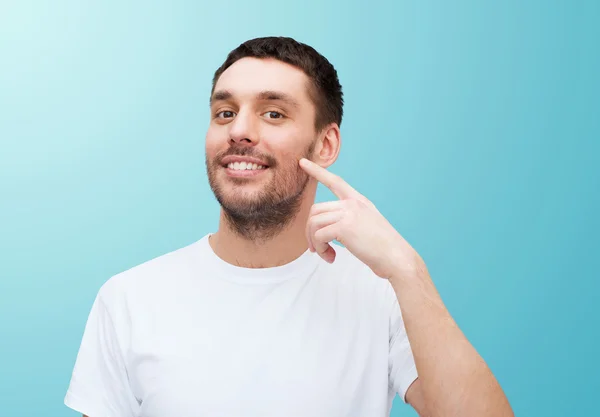 Sonriente joven guapo apuntando a la mejilla —  Fotos de Stock