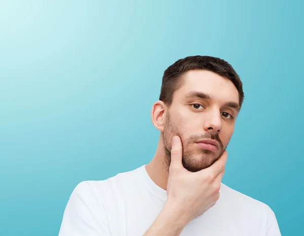 Schöner ruhiger Mann, der sein Gesicht berührt — Stockfoto