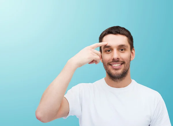 Lächelnder junger gutaussehender Mann zeigt auf die Stirn — Stockfoto