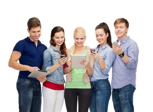 Lachende studenten met behulp van smartphones en tablet pc — Stockfoto