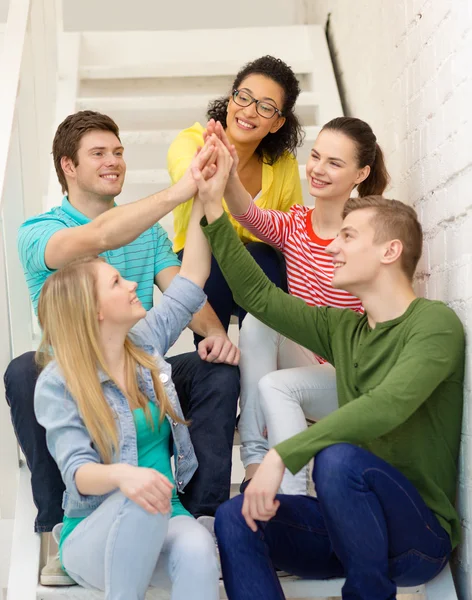 Smiling students making high five gesture sitting — Stock Photo, Image