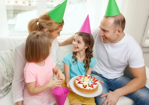 Lächelnde Familie mit zwei Kindern in Hüten mit Kuchen — Stockfoto