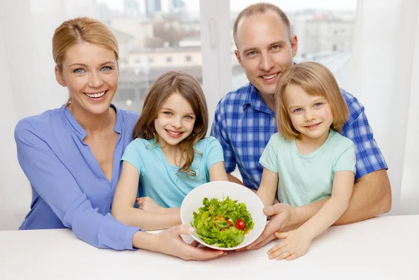Счастливая семья с двумя детьми с салатом дома — стоковое фото