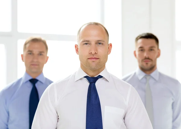 Serious businessman in office with team on back — Stock Photo, Image