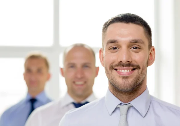 Lachende zakenman in kantoor met team op rug — Stockfoto