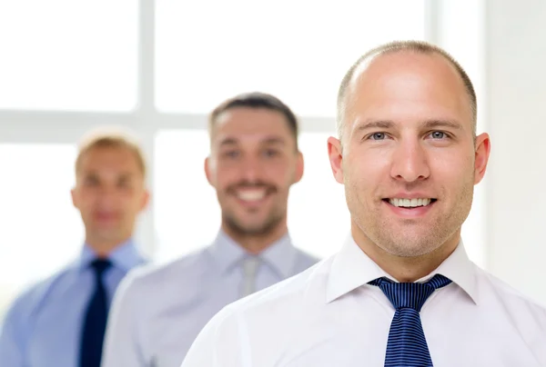 Hombre de negocios sonriente en la oficina con el equipo en la espalda — Foto de Stock