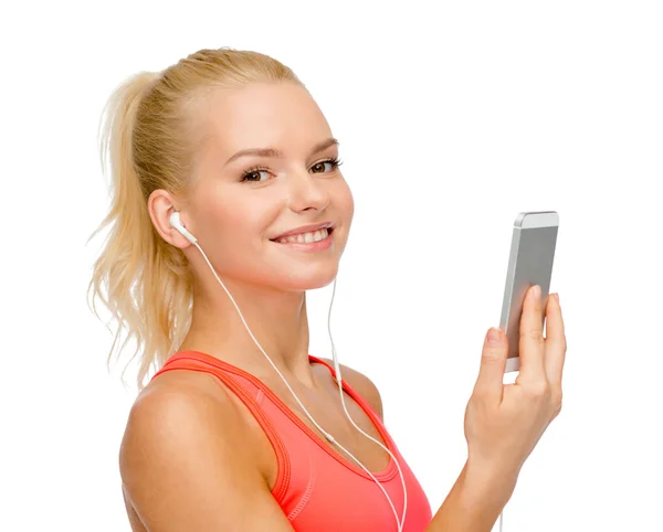 Sorrindo mulher desportiva com smartphone e fones de ouvido — Fotografia de Stock