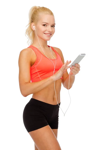 Усміхнена спортивна жінка зі смартфоном та навушниками — стокове фото