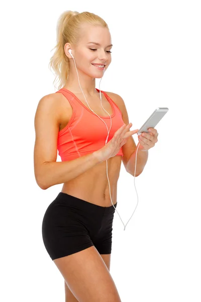 Mujer deportiva sonriente con teléfono inteligente y auriculares —  Fotos de Stock