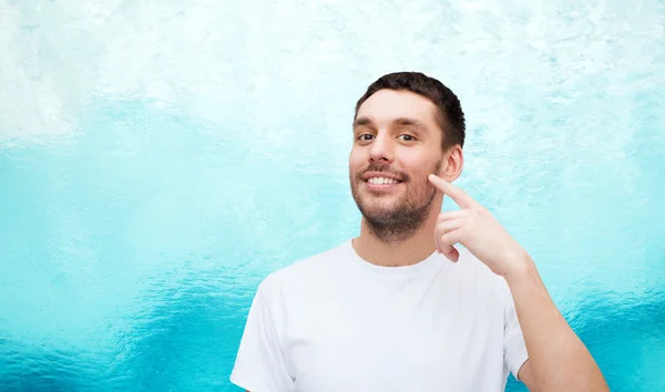 Sonriente joven guapo apuntando a la mejilla —  Fotos de Stock