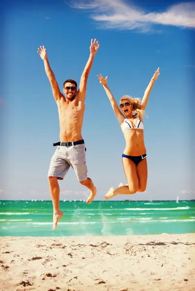 Casal feliz pulando na praia — Fotografia de Stock