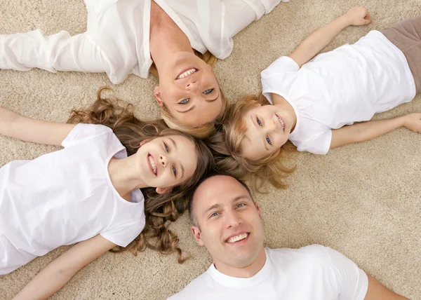 Parents and two girls lying on floor at home — Stock Photo, Image