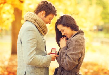 man proposing to a woman in the autumn park clipart