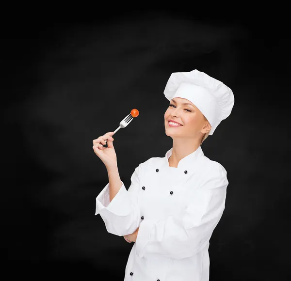 Çatal ve domates ile gülümseyen kadın aşçı — Stok fotoğraf